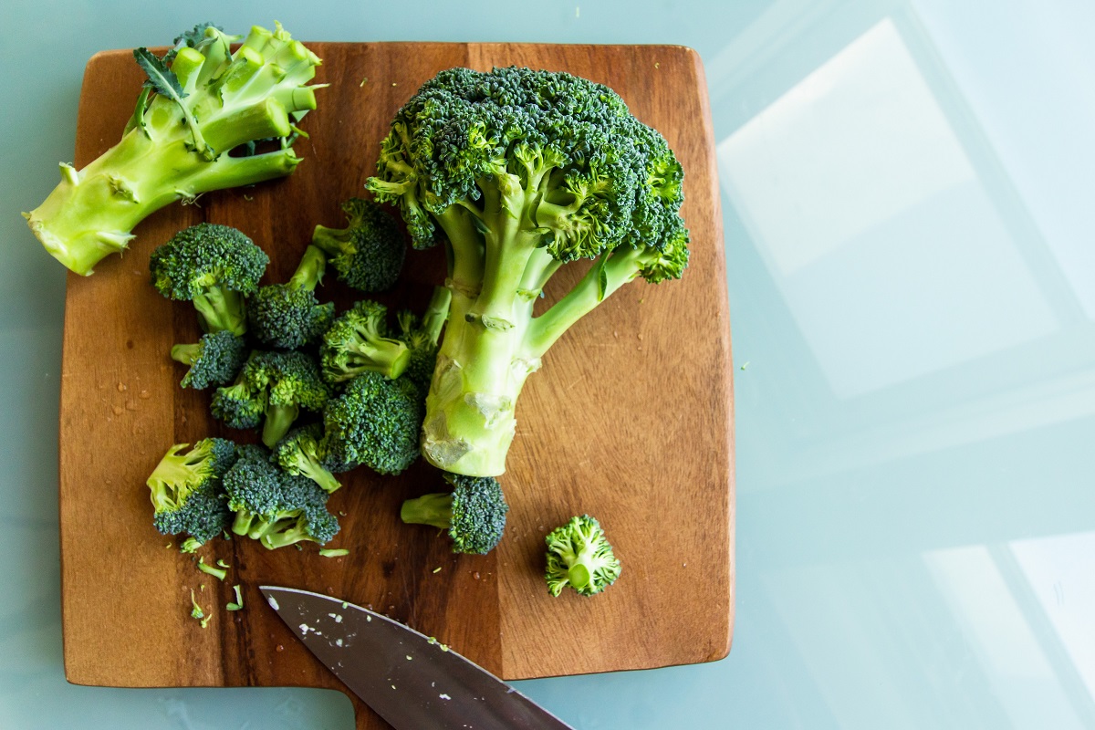broccoli asezat pe un tocator, pe fundal albastru, ca ingrediente sănătoase la salată