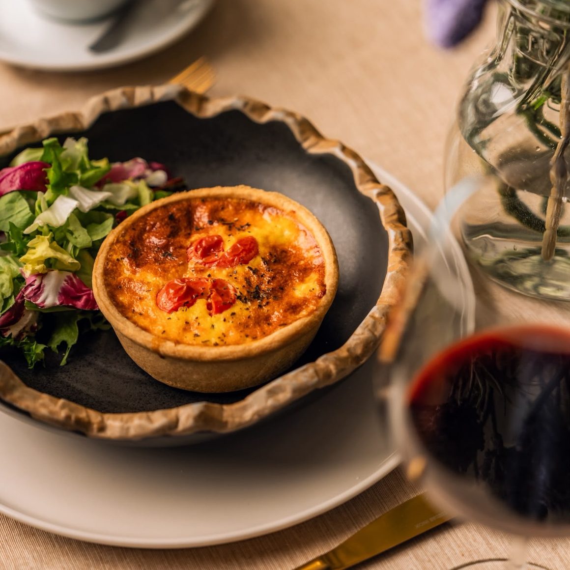Quiche cu salată și cappuccino, servite la masă la Boutique du Pain, unul dintre restaurantele cu meniu de prânz din București