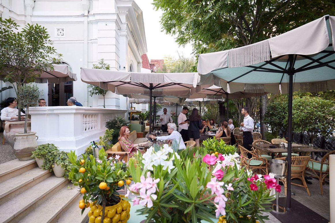 Grădina Casa Fratelli, printre cele mai frumoase din centrul Bucureștiului, cu umbrele și flori de vară. unul dintre restaurantele cu meniu de prânz din centrul Bucureștiului