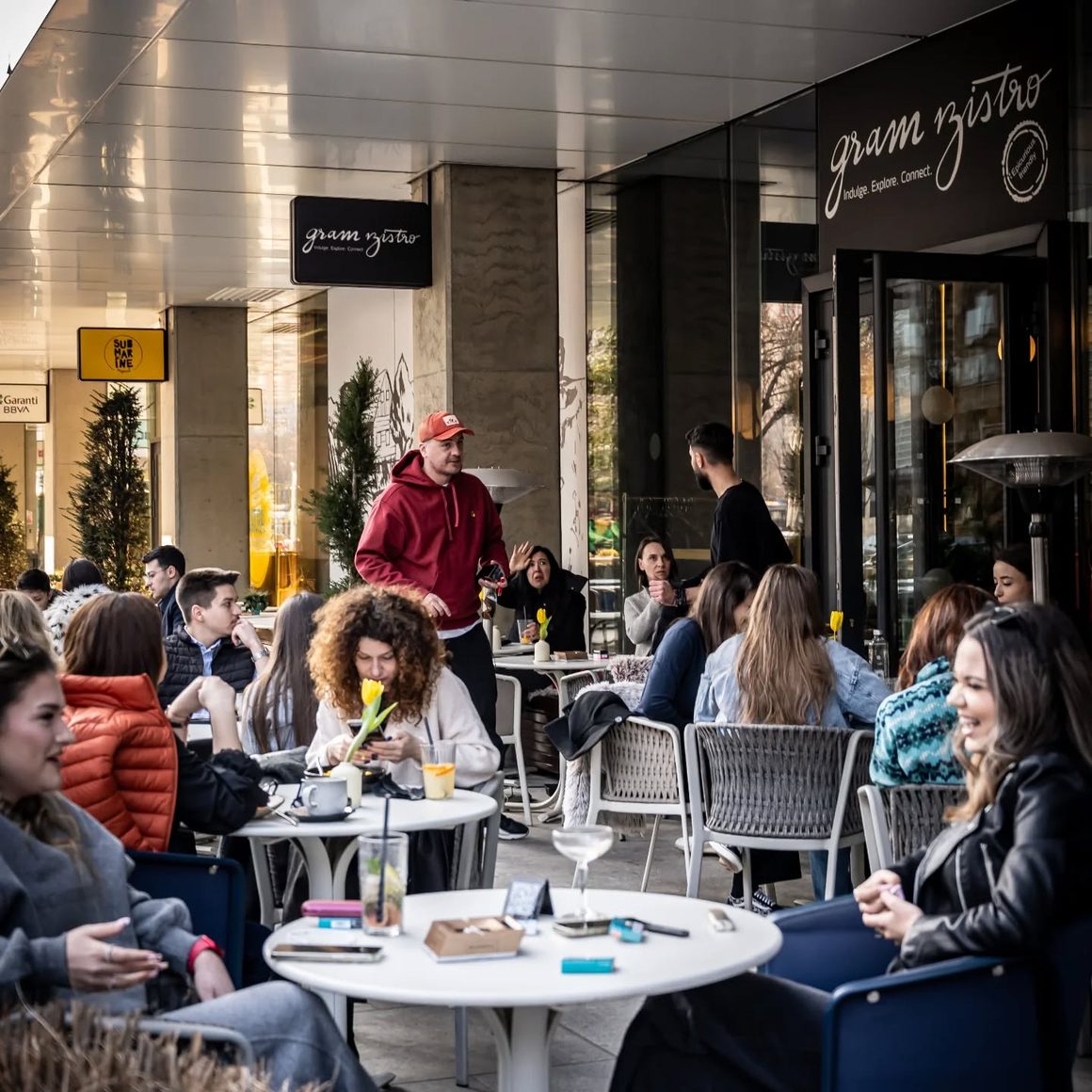 Terasa Gram Bistro din Piața Victoriei, plină la prânz, cu mese ocupate afară