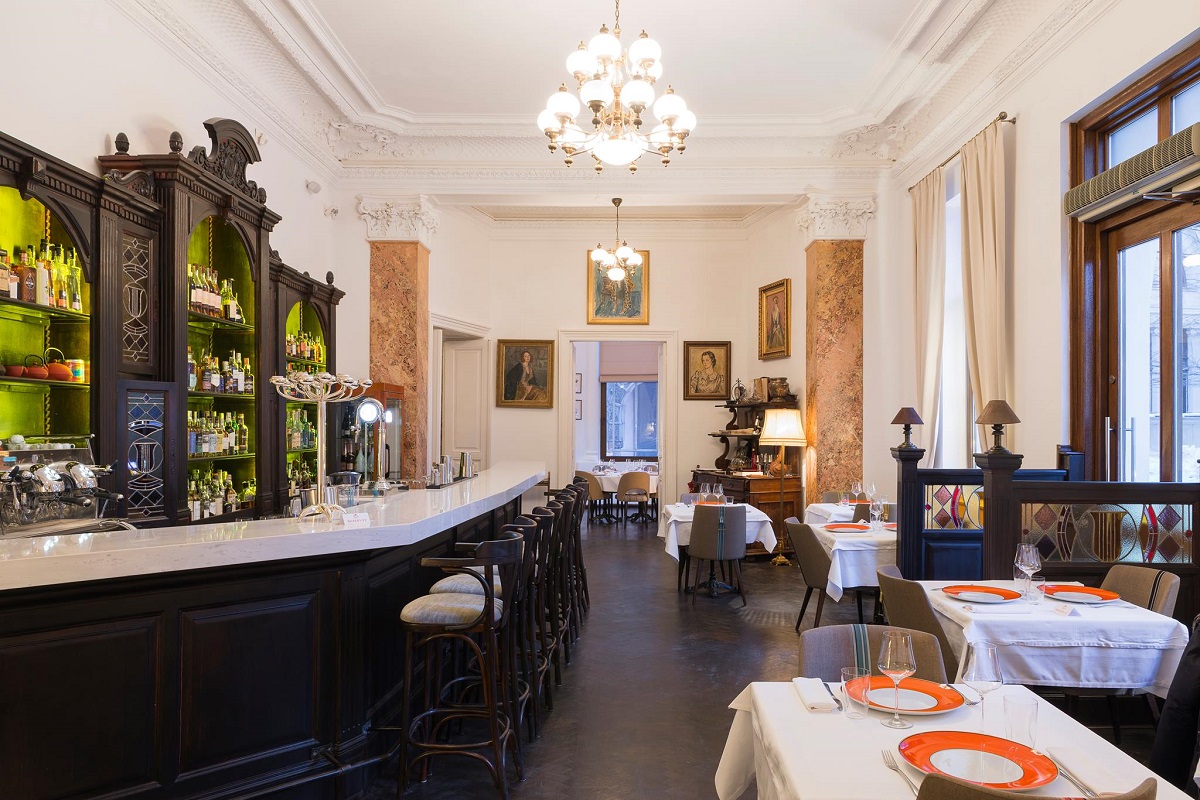 sala de mese de la Relais & Châteaux Le Bistrot Français, cu barul in stanga si mese pe partea dreapta, in partea geamurilor, unul din restaurante franțuzesști din București, decorat in stil clasic