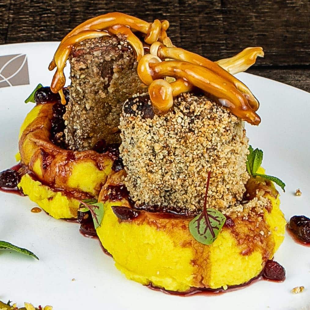 Medalion de mistreț în crustă de alune cu ciuperci caramelizate, sos de merișoare și piure de cartof de la Sergiana. Restaurante din Brașov