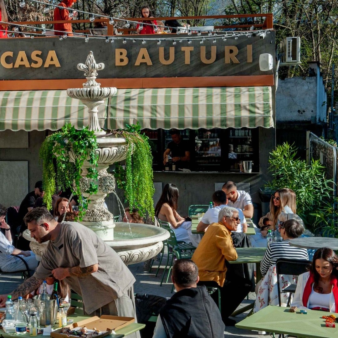 Piațeta Cotroceni cu terasă stradală, fântână decorativă și locuri de dining în aer liber.