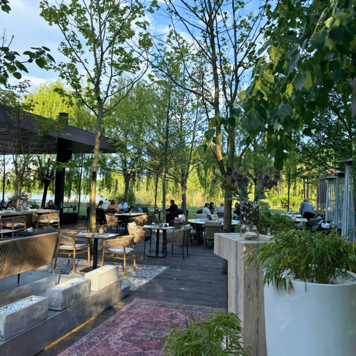 Terasa Bosco Gourmet Nest cu zonă de dining outdoor, copaci și spații verzi amenajate.