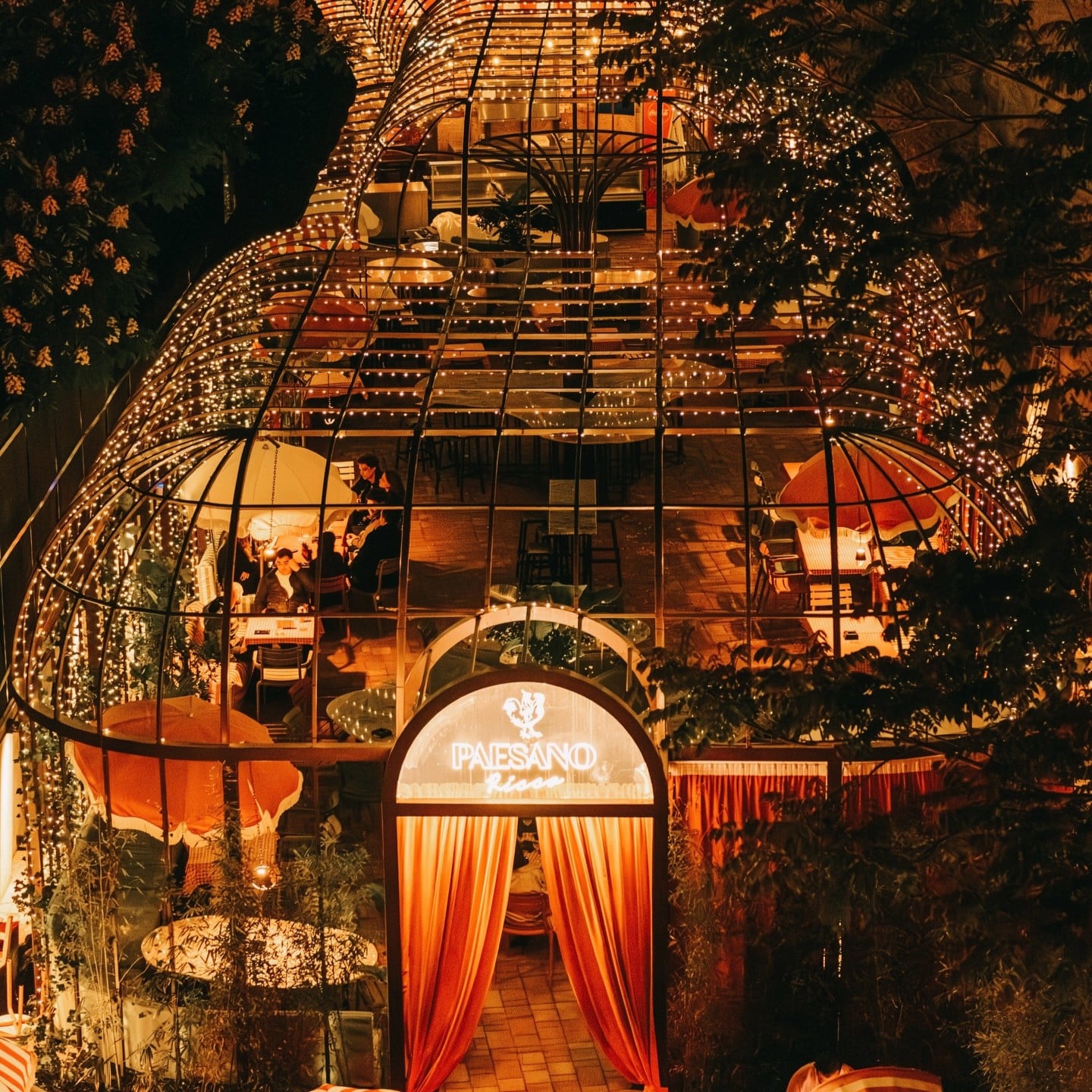 Terasa La Grande Bellezza București iluminată seara, cu structură metalică decorată cu lumini și mese pentru restaurant.