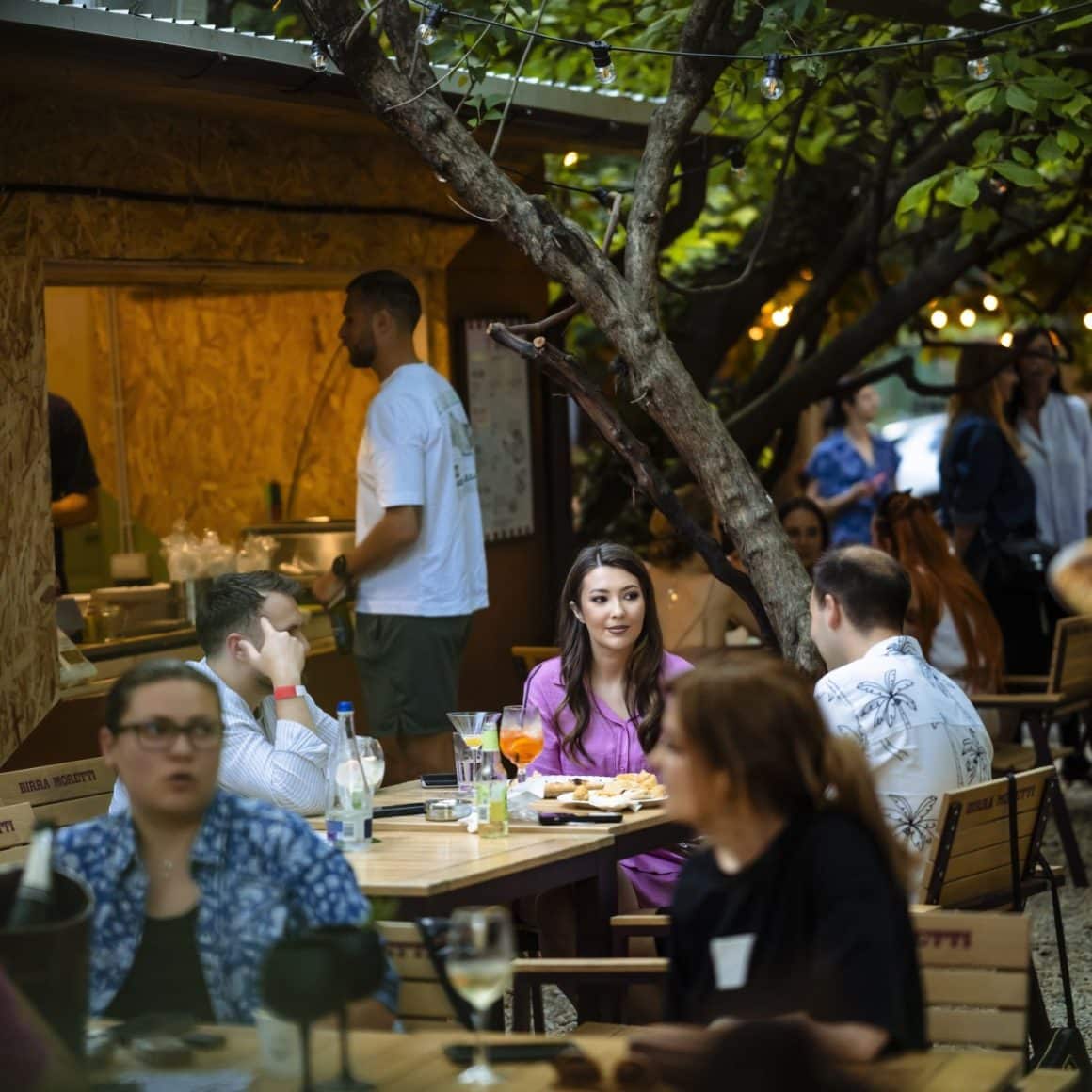 Mai multi oameni la mese pe terasa in grădina Sip Pop-Up Garden. Terase București