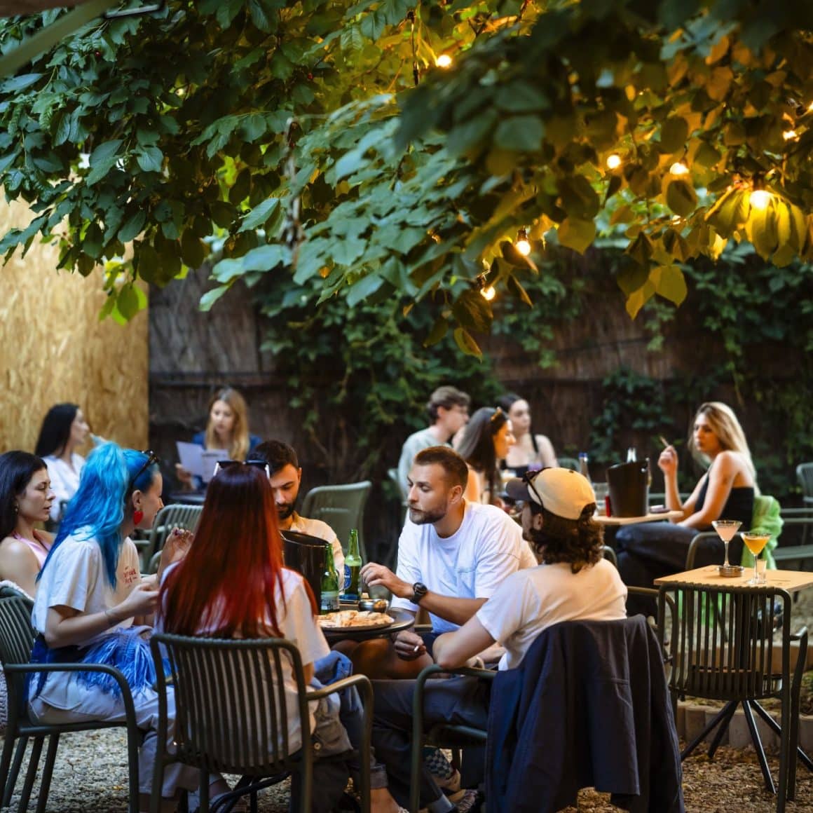 Mai multi oameni la mese pe terasa in grădina Sip Pop-Up Garden. Terase București