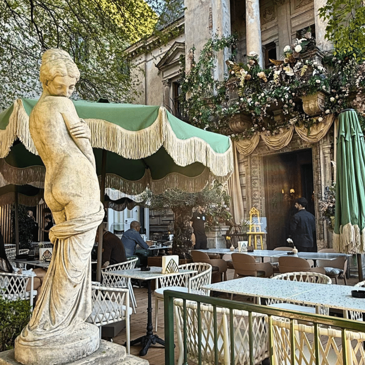 Terasa Grand Café du Bucharest, amenajată în curtea unei vile istorice din București, cu statuie decorativă și locuri de dining în aer liber. Una din cele mai frumoase terase din București
