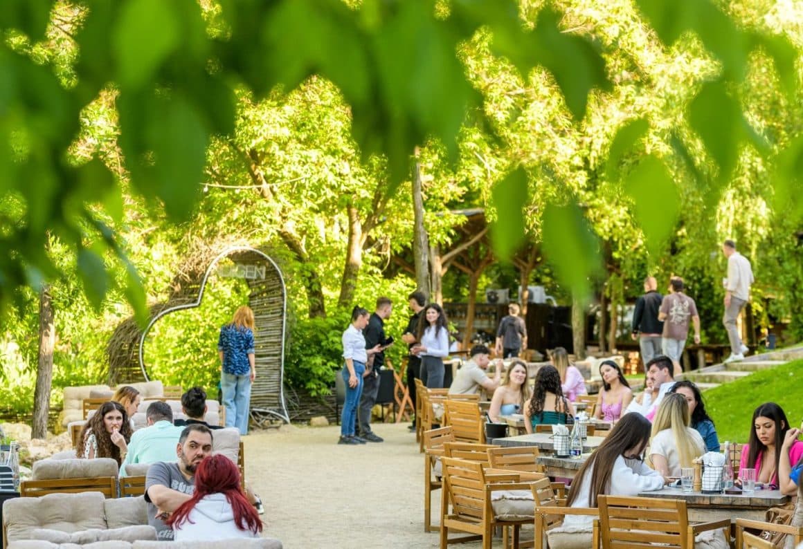 Terasa Indigen Space for Soul din București, plină de oameni la mese pe nisip, cu vedere la Lacul Tei vara