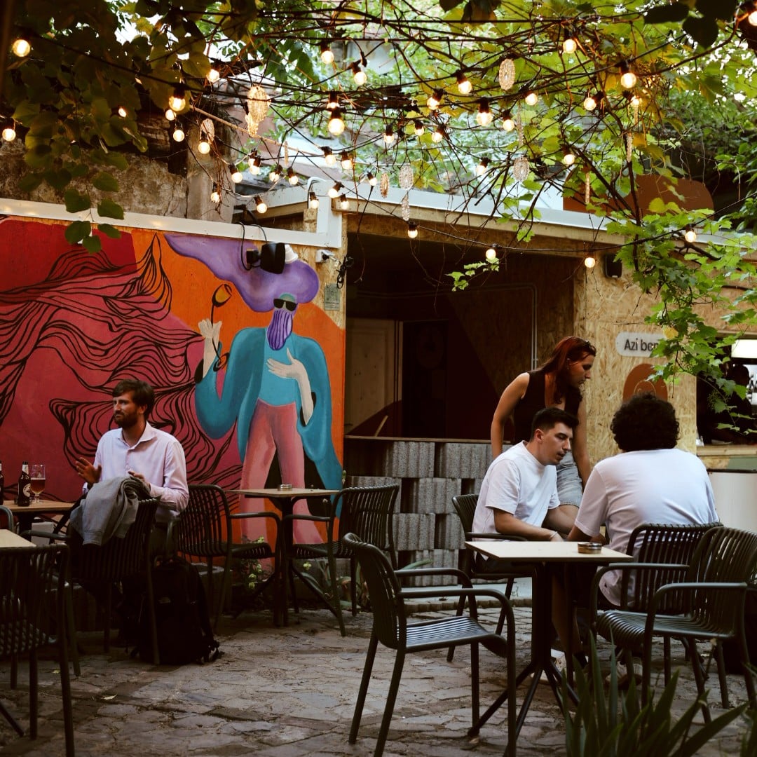 Mai multi oameni la mese pe terasa in grădina Sip Pop-Up Garden. Terase București