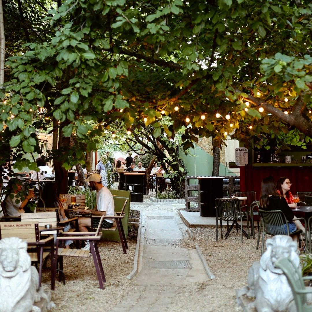 Mai multi oameni la mese pe terasa in grădina Sip Pop-Up Garden. Terase București