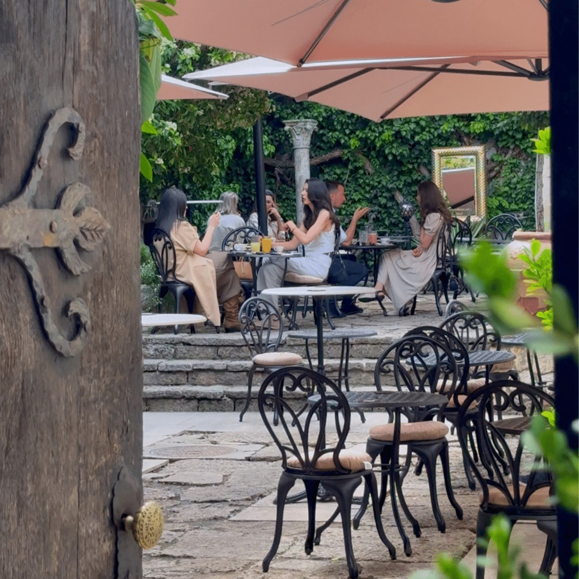 Terasa Art Deco Café din București, cu mese în aer liber, umbrele și zonă de grădină interioară.