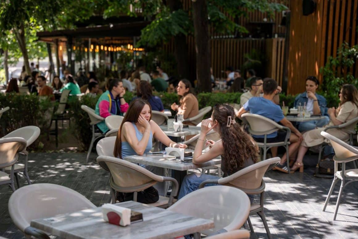 Terasa The Moon Brasserie din București, cu mese în aer liber, zonă umbrită și clienți serviți la restaurant. Terase București