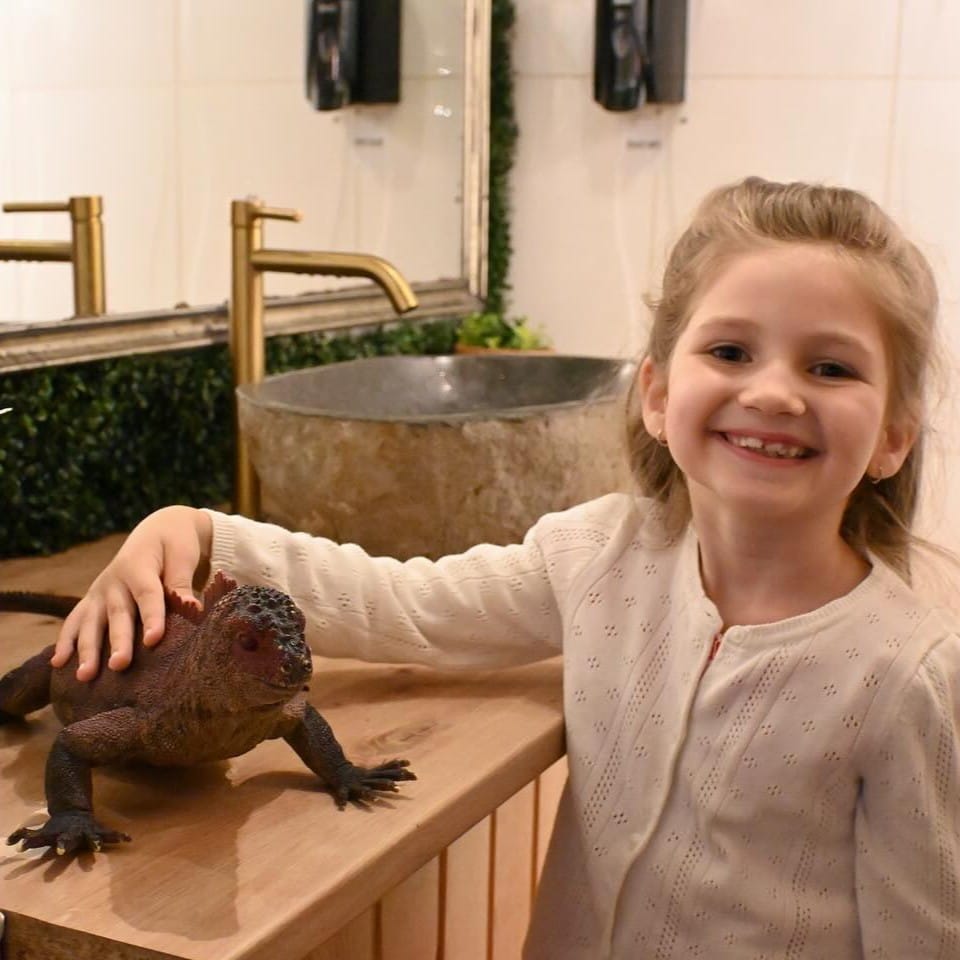 O fetiță mângâie o iguană la ZooCafe București. Restaurante și terase kids friendly București