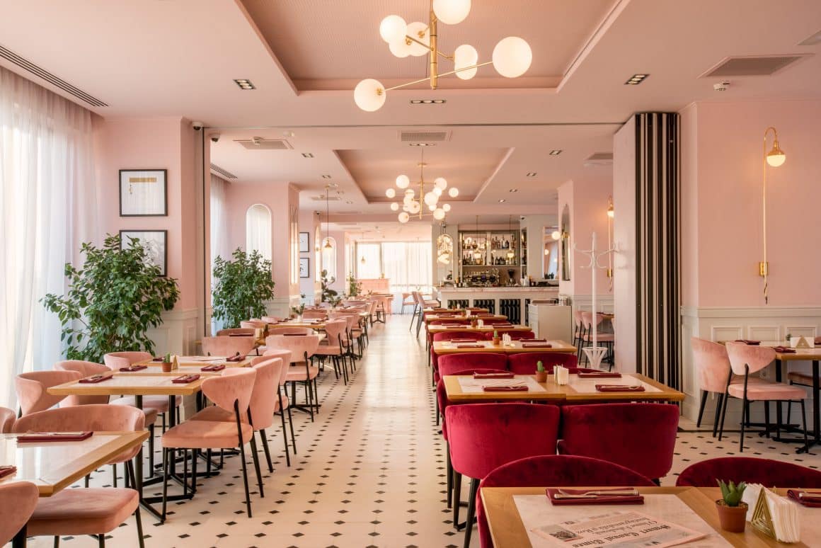 restaurante 8 martie: imagine de ansamblu din cismigiu bistro la etaj, in care se vede tot restaurantul, cu un rand de scaune pe stanga, cu scaune roz, alt rand de mese in dreapta, cu scaune visinii din catifea, pereti roz, corpuri de iluminat suspendate si podea mozaic, in alb si negru