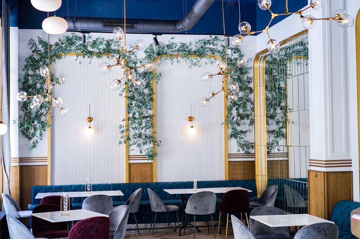 Restaurantul Ergo din București, cu pereti albi in stil clasic, pe care sunt arcade din plante si lampi ambientale, cu mese albe, scaune si canapele