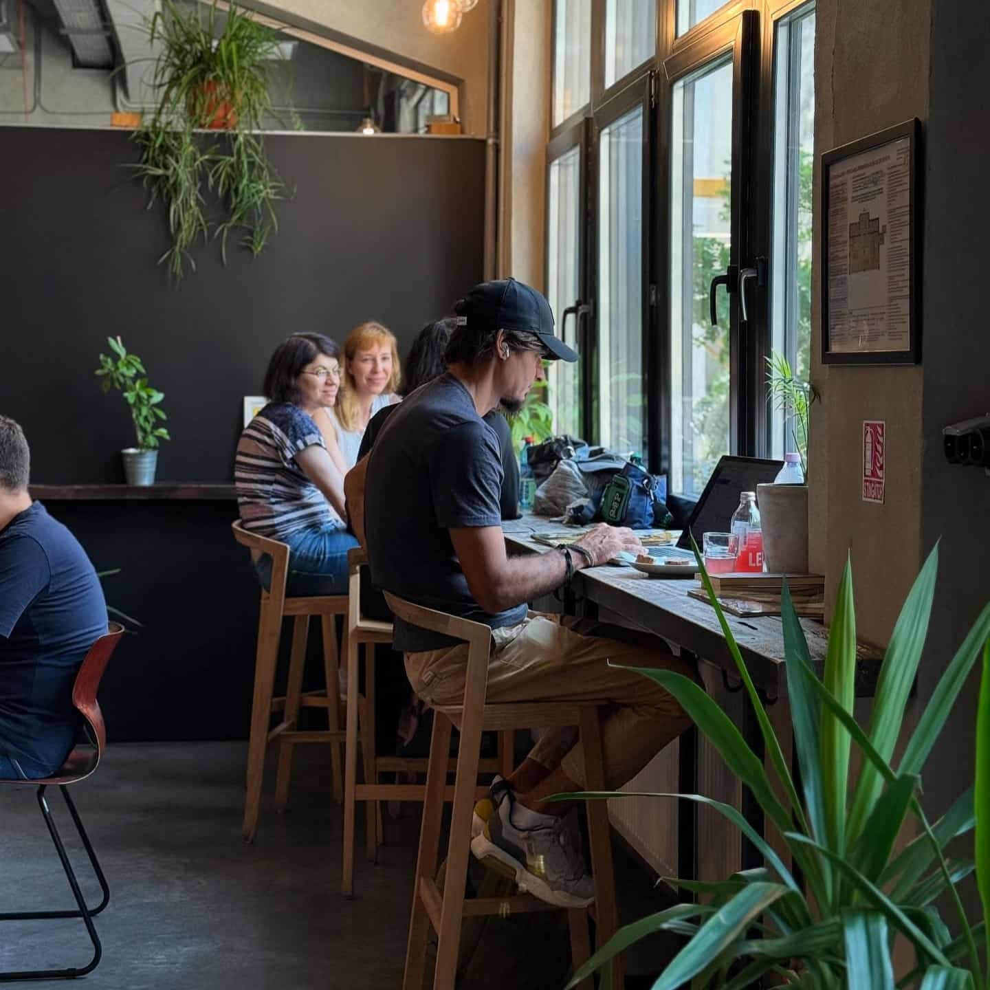mai mulți oameni la masa in cafeneaua Beans & Dots de la Palatul Universul, dintre care unul sta pe laptop.