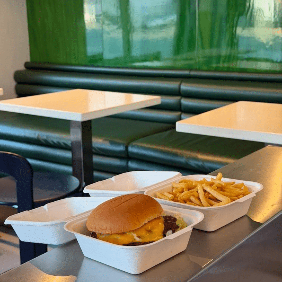 Burger Smash Baby cu brânză topită, servit în cutie to-go, alături de cartofi prăjiți, în locația Smash Baby Dorobanți