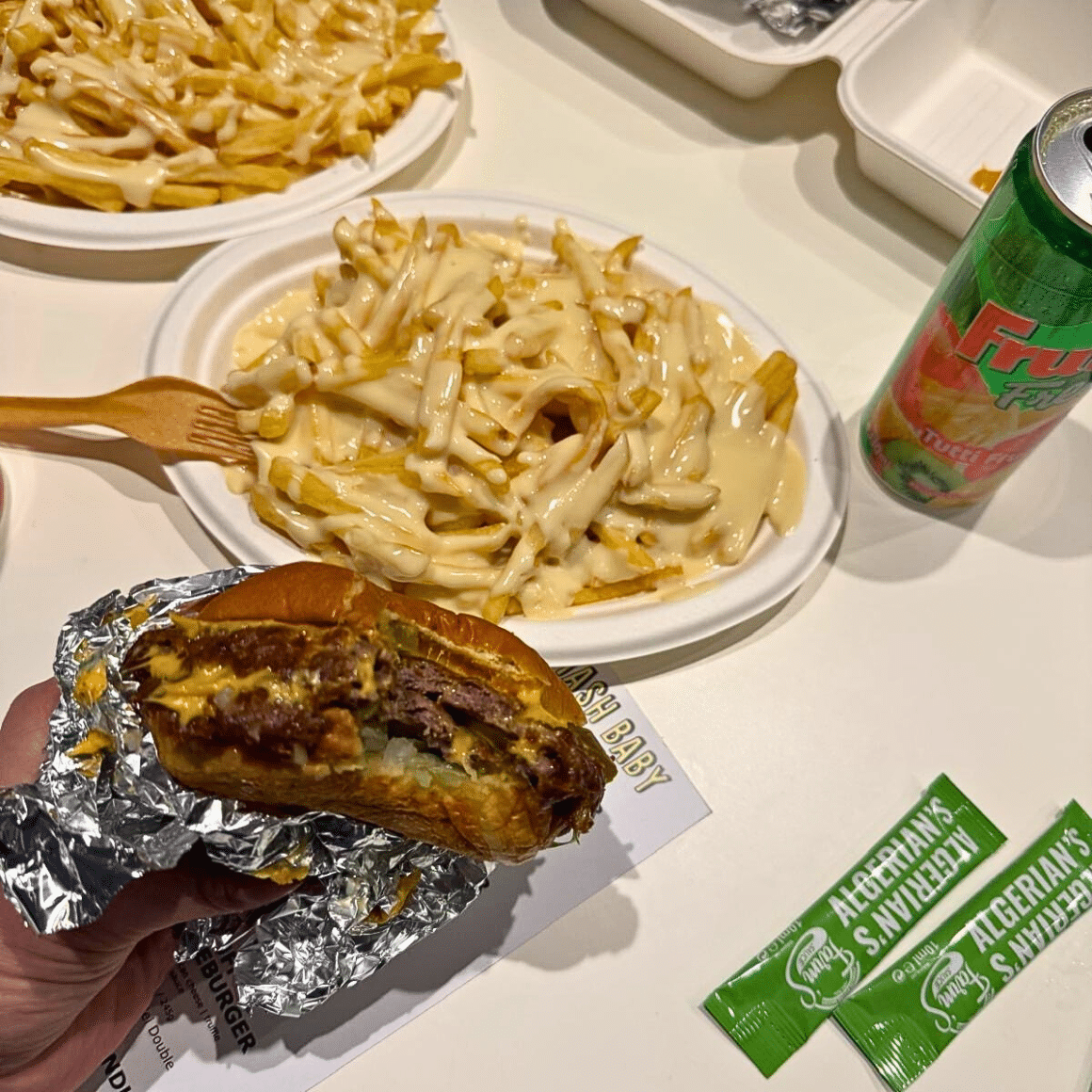 Burger suculent de la Smash Baby, mușcat, cu cartofi acoperiți în sos de brânză lângă — cei mai buni burgeri din București