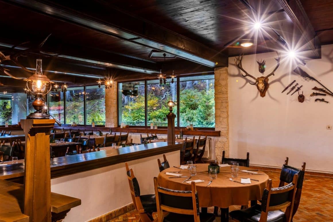 Interior Restaurant Vânătorul Poiana Brașov – sală rustică cu specific vânătoresc și vedere spre pădure