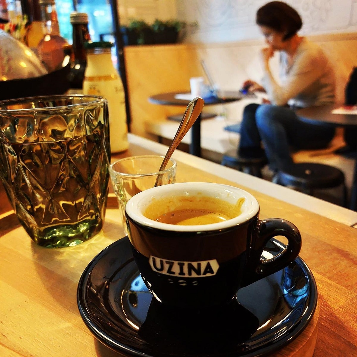 o ceașcă de cafea este așezată pe un platou de lemn, alături de un pahar cu apă