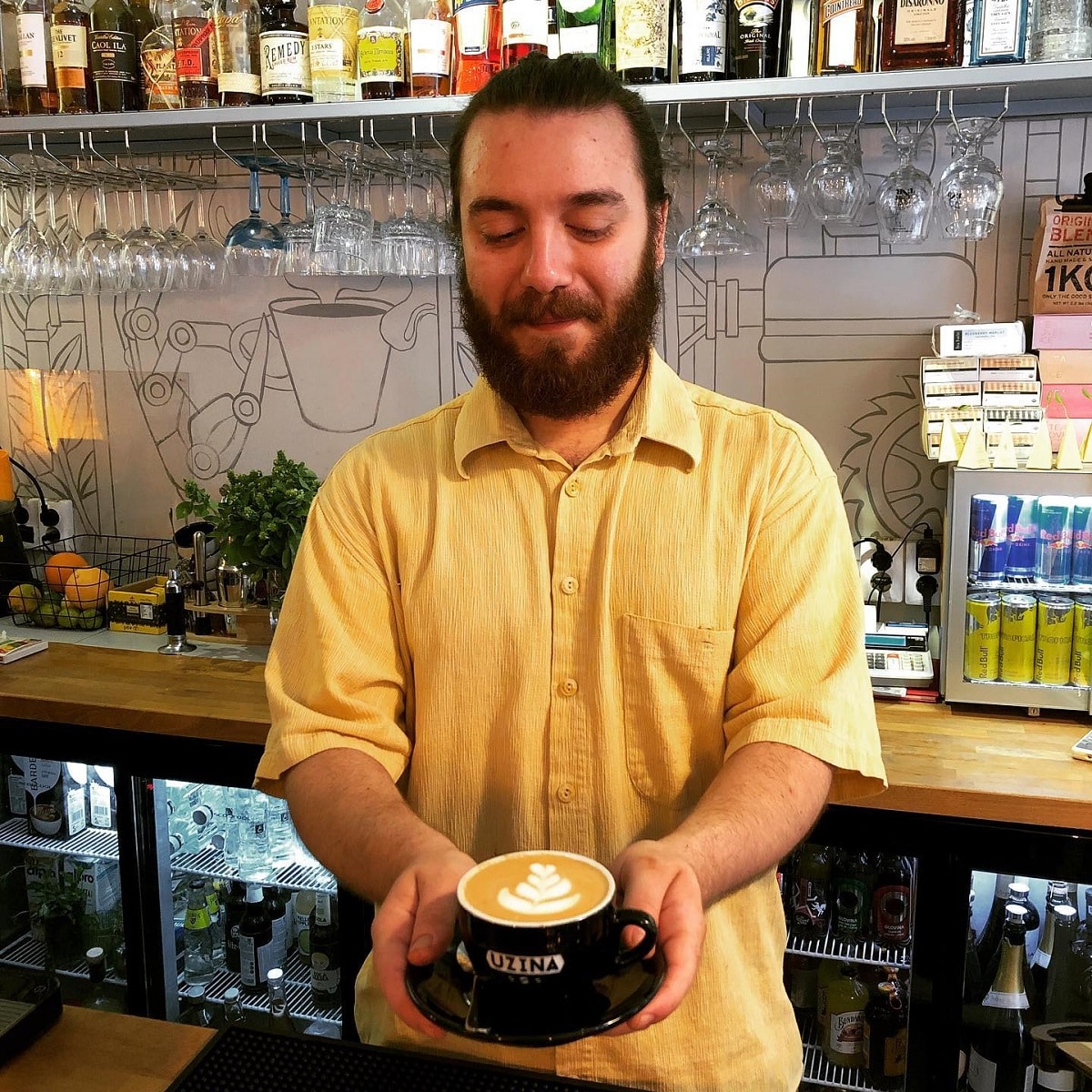 un barista ține cu două mâini o ceașcă de cafea proaspăt făcută