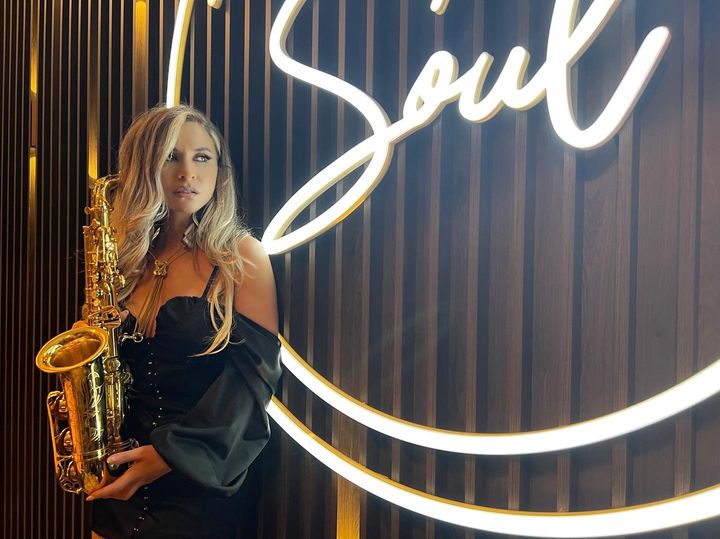 o cântareață de jazz cu un saxofon pe scena restaurantului One Soul din Brasov, unul din localuri cu muzică jazz din țară