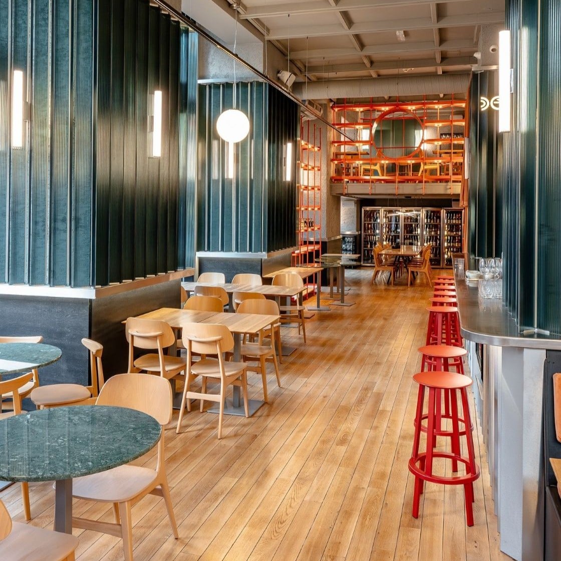 Interior DeSoi București, restaurant și wine bar cu mese din lemn, taburete roșii la bar și rafturi cu sticle de vin în fundal — o alegere relaxată pentru brunch de restaurante 8 martie