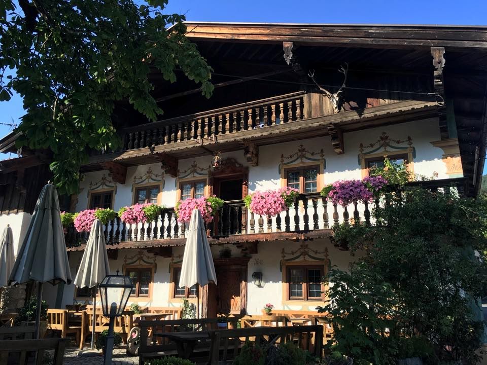 Restaurant pitoresc din Alpii Bavarezi cu flori la balcoane și gradina primitoare.