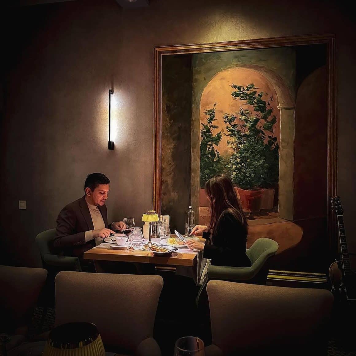 Cuplu la cină intimă la Poesia București, restaurant italian fine dining, cu tablou mural și lumini calde, unul din cele mai bune restaurante 8 martie pentru o seară în doi