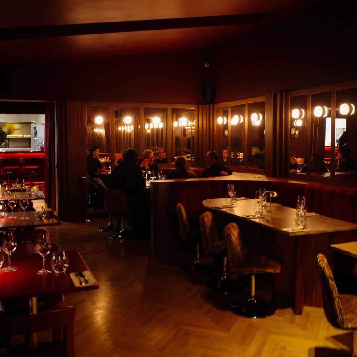 Interior Tabra restaurant București, cu lumini calde de tip cabină de machiaj, banchete curbe din lemn întunecat și atmosferă intimă de bistro contemporan