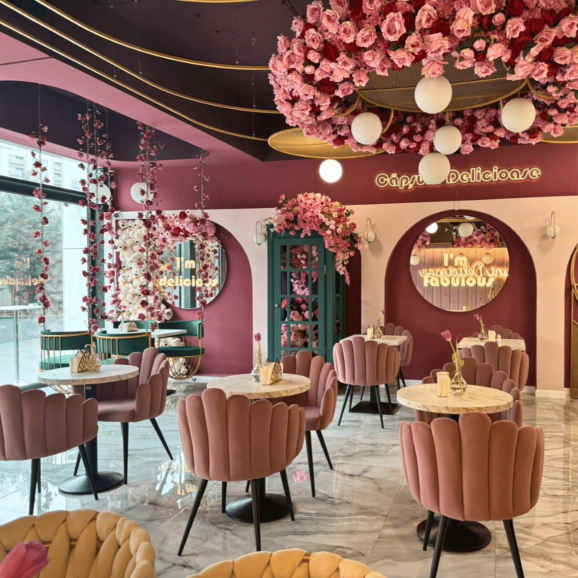 Interior Zola Bistro București, cu scaune roz din catifea în formă de floare, tavan acoperit cu flori roz și instalații aurii, oglinzi rotunde cu mesaje neon și decor floral abundent. Restaurante pentru 8 Martie