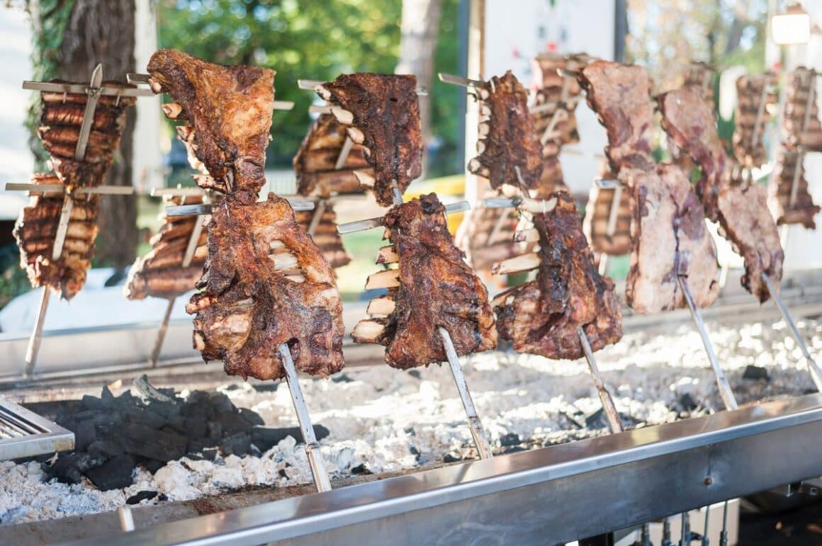 mai multe bucati de carne sunt puse la gatit deasupra unui gratar cu carbuni, traditional argentinei. asado