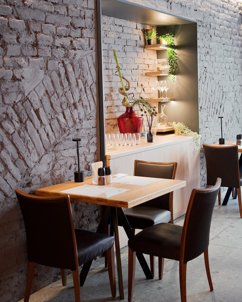 masa langa un perete cu caramida aparenta, iar in fundal rafturi cu stilce de vin la restaurant Eat It din Oradea