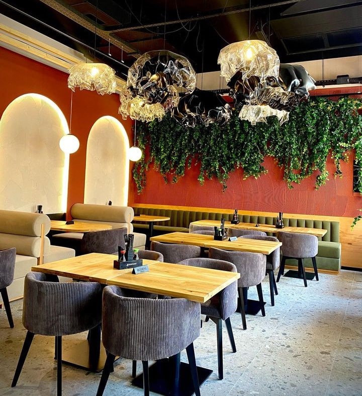 imagine din restaurant Kintaro, Oradea, cu pereti caramizii, mese de 4 persoane cu scaune capitonate si decor din plante verzi