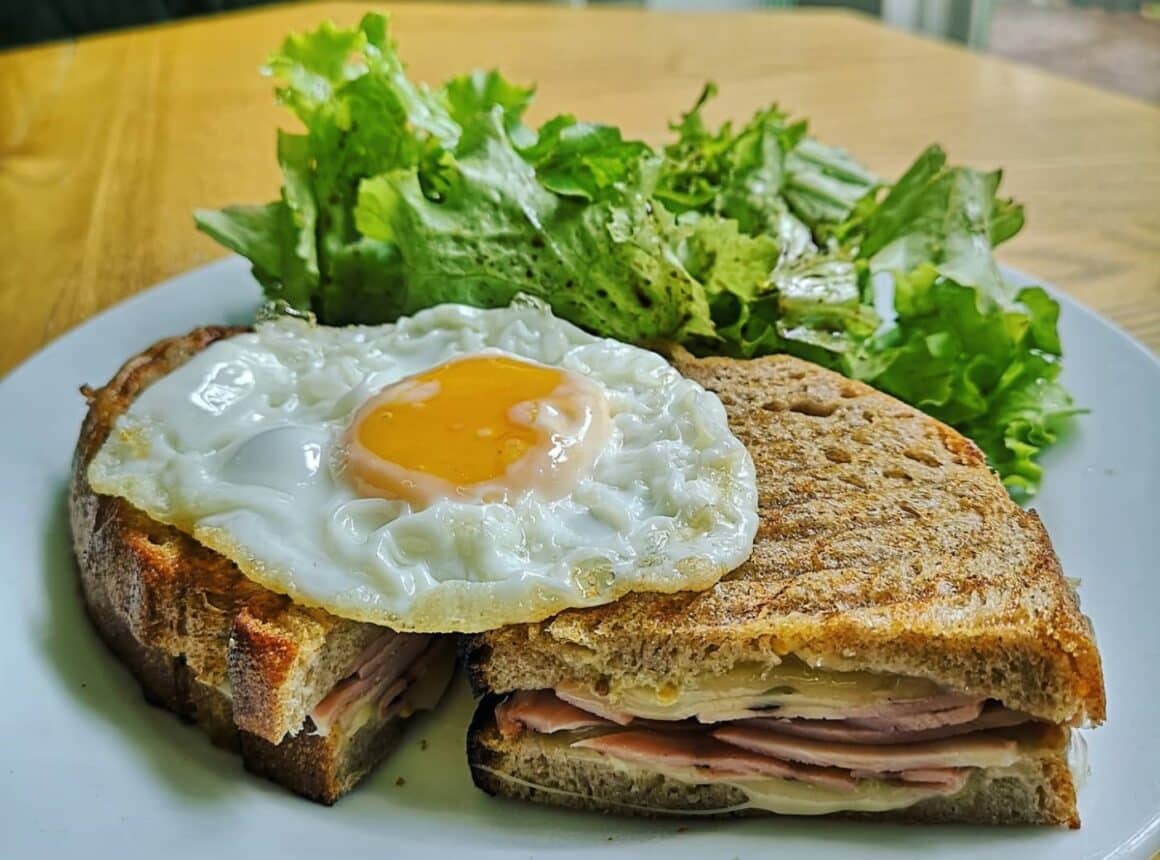 Sandwich cald cu jambon de porc, brânză Gouda, sos de muștar franțuzesc cu maioneză, ou ochi și pâine integrală cu maia. Croque Madam, sandvișuri celebre.