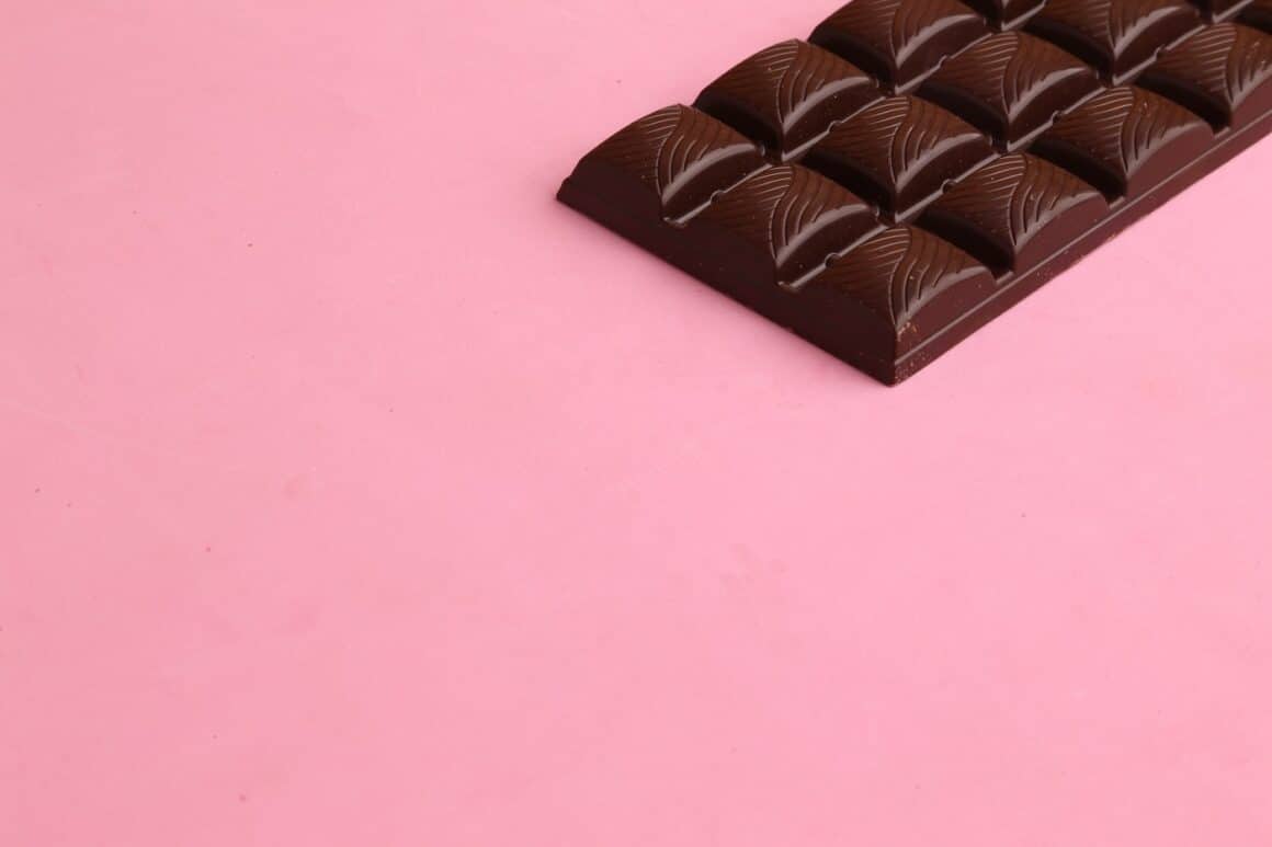 bucata de ciocolata neagra fotografiata pe fundal roz - alimente care taie foamea