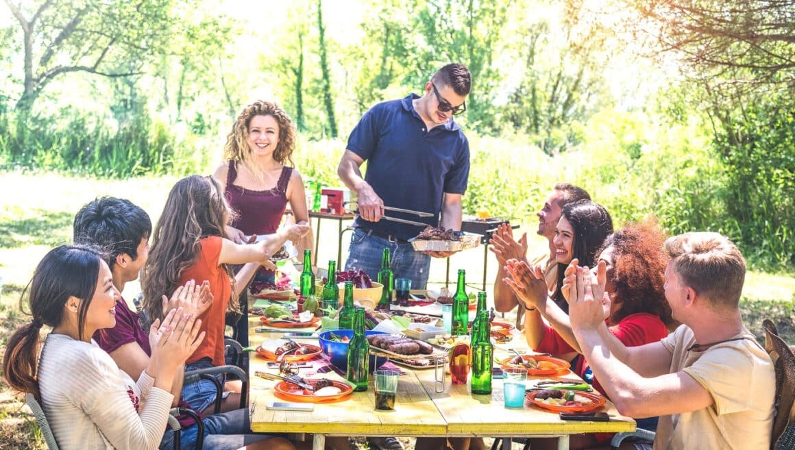 masa mare cu prieteni la o petrecere de picnic ina er liber. CUm să faci cel mai bun grătar