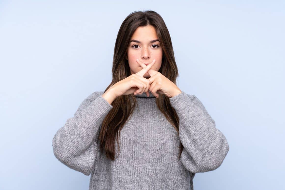 Teenager Brazilian girl over isolated blue background showing a sign of silence gesture