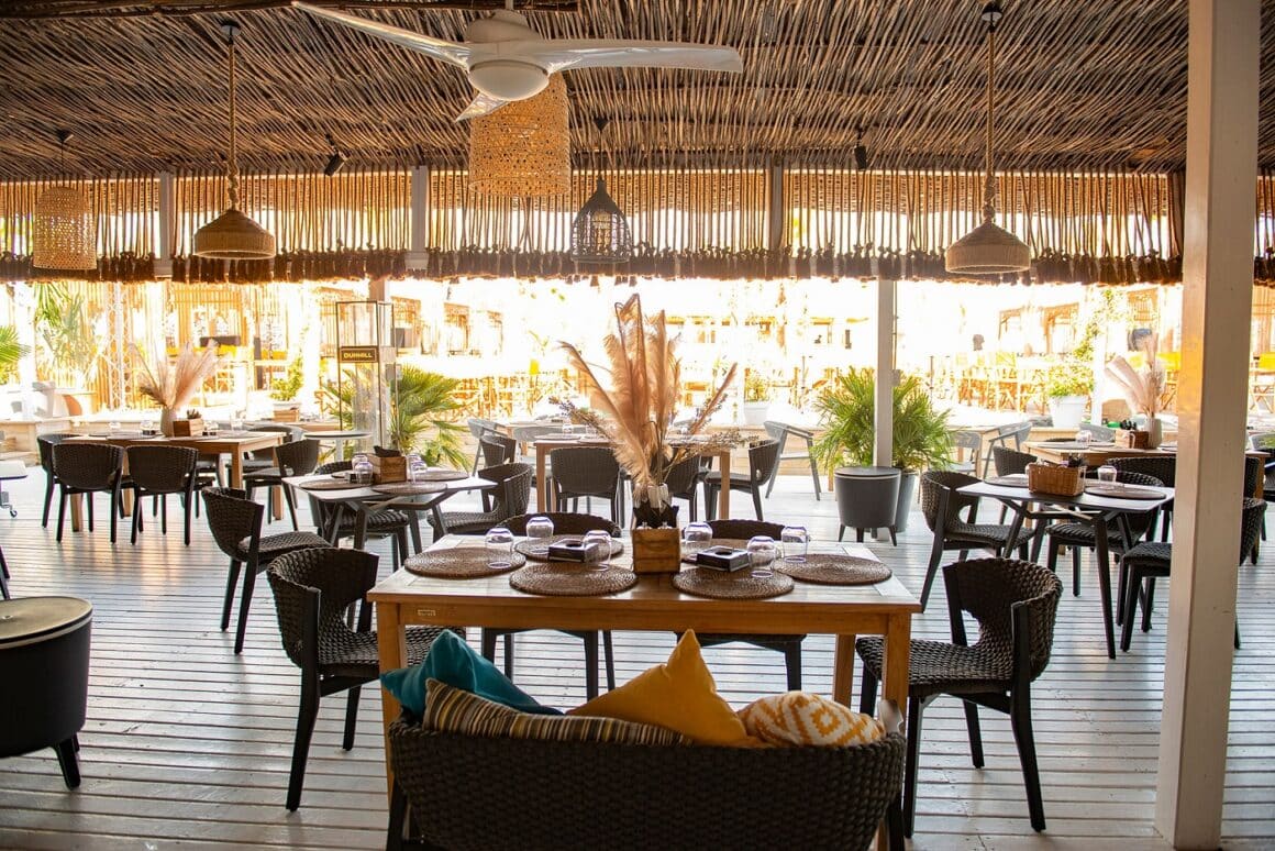 terasa restaurantului La Nueva Cucaracha din Mamaia, fotografiata ziua, cu tavan din nuiele, podea de lemn si mese pe plaja in fundal