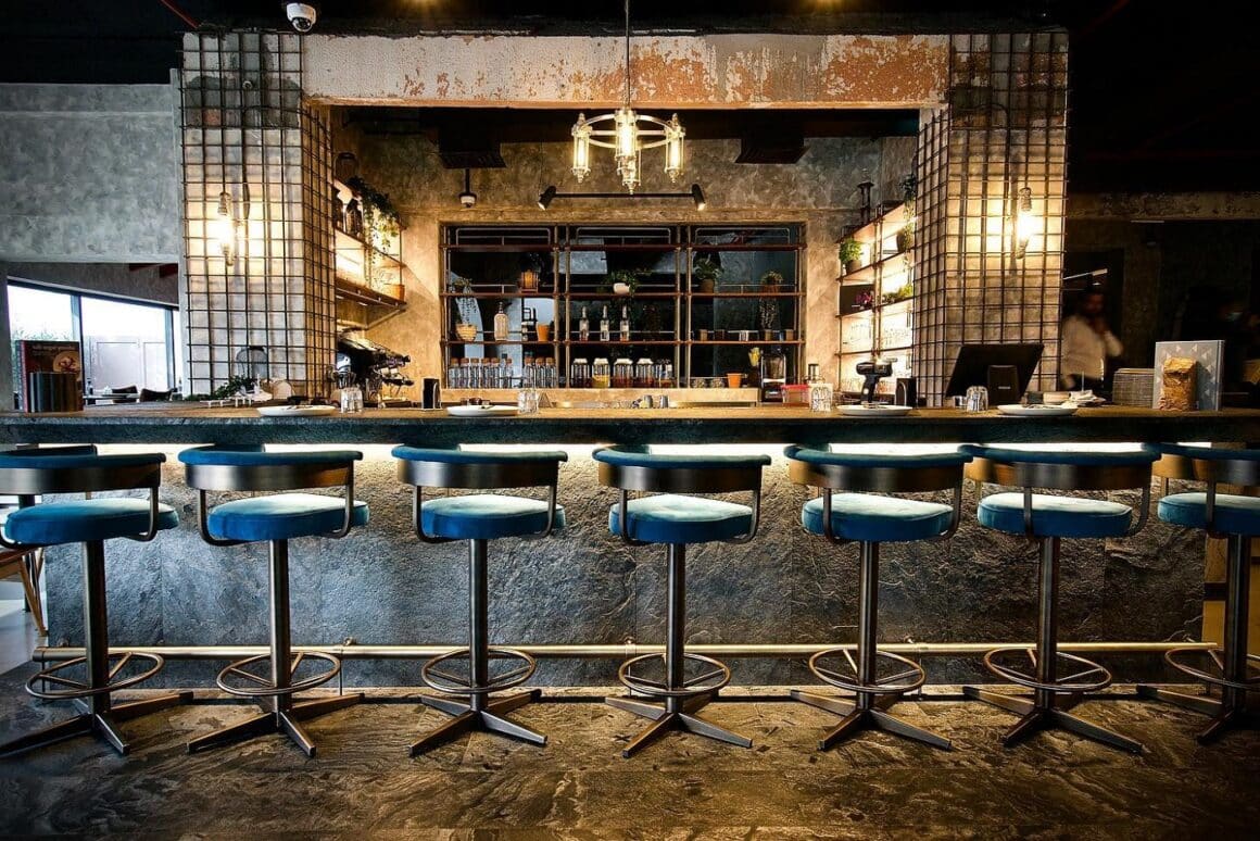Bar elegant, de lux, cu scaune inalte si in fundal rafutir cu bauturi si oglinzi la restaurant 11 Woodfire. Top restaurante Dubai