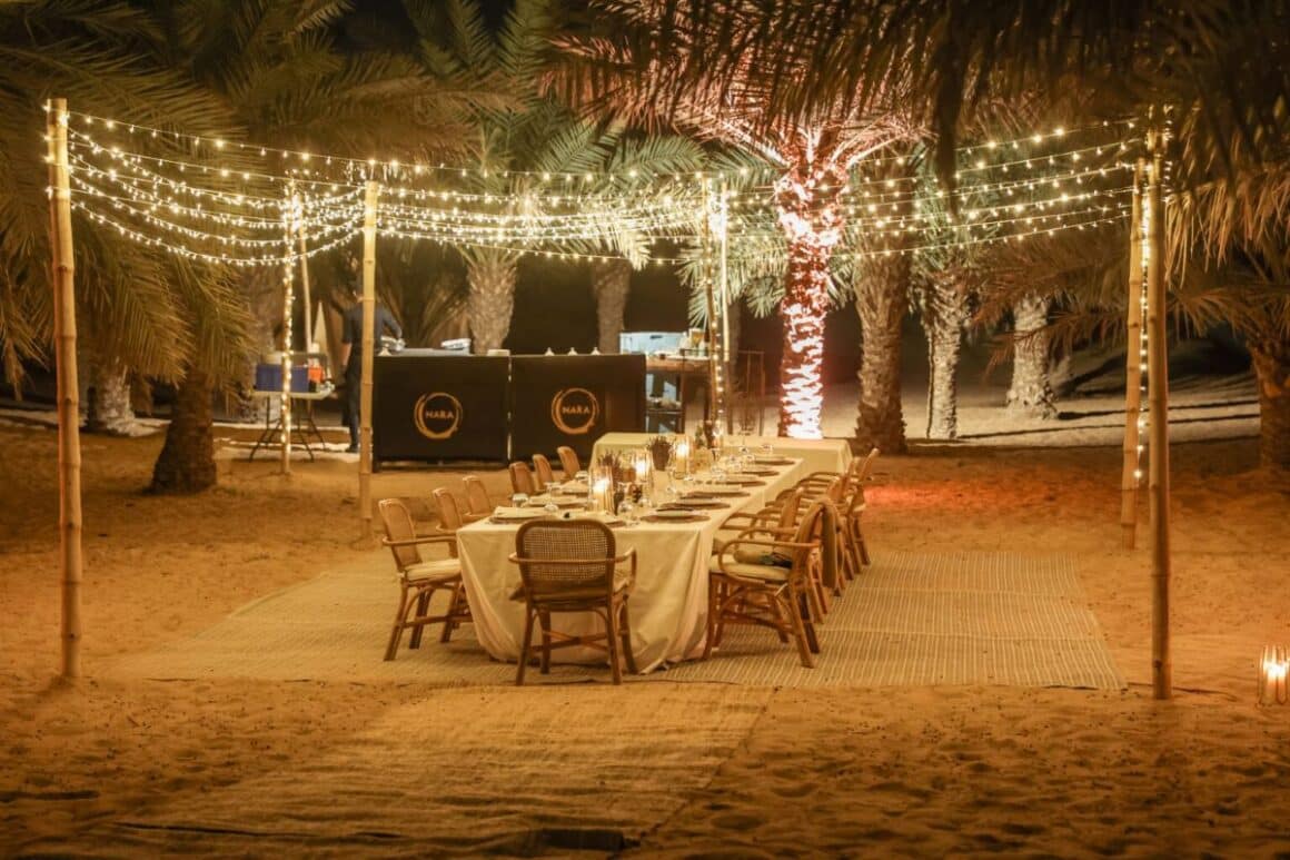 masa festiva seara, printre palmieri, cu luminite decorative la Sonara Camp