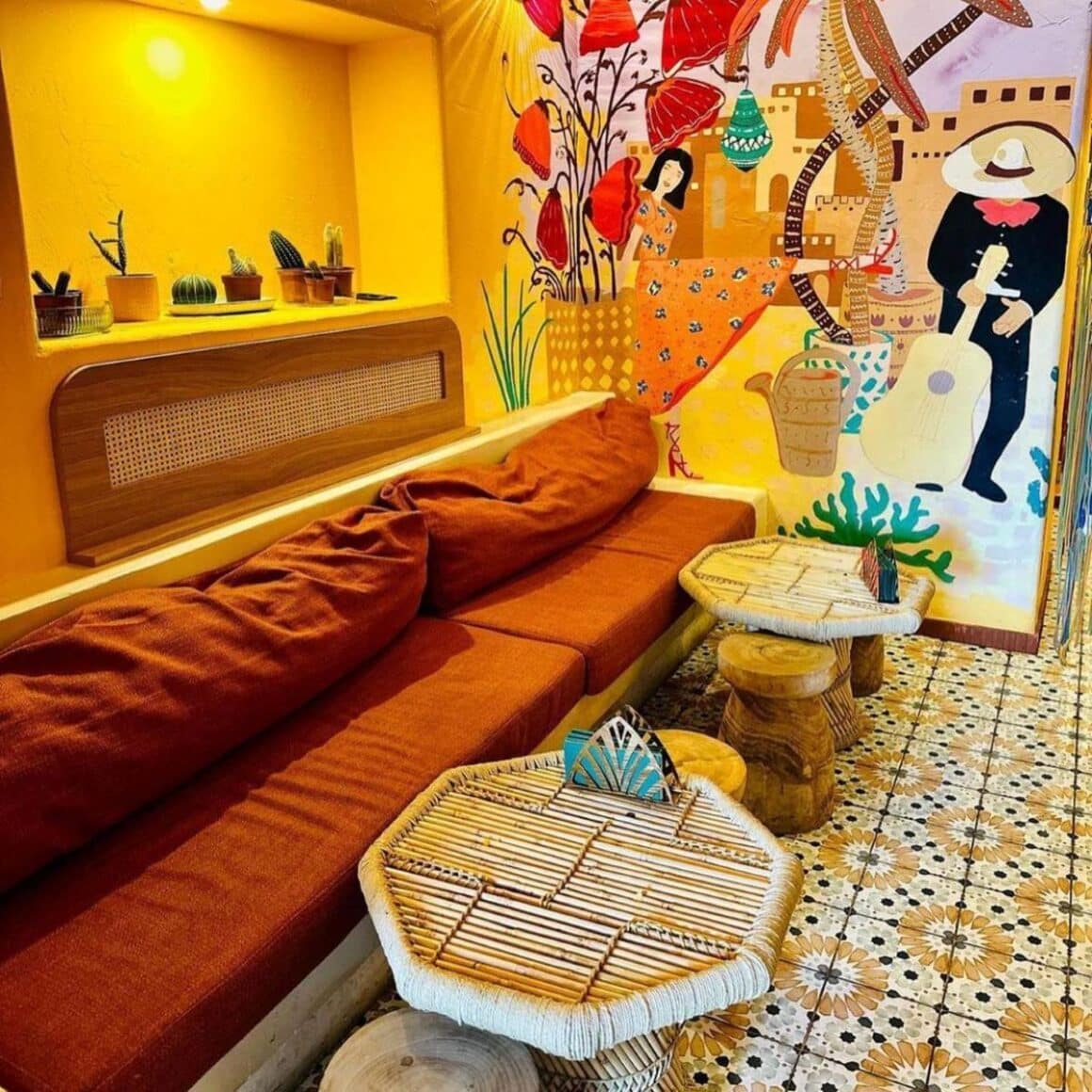 interiorul restaurantului Los Amantes, cu pereti vopsiti galben si multe detalii pictate, floarale, o canapea lunga si 2 mese micute in fata