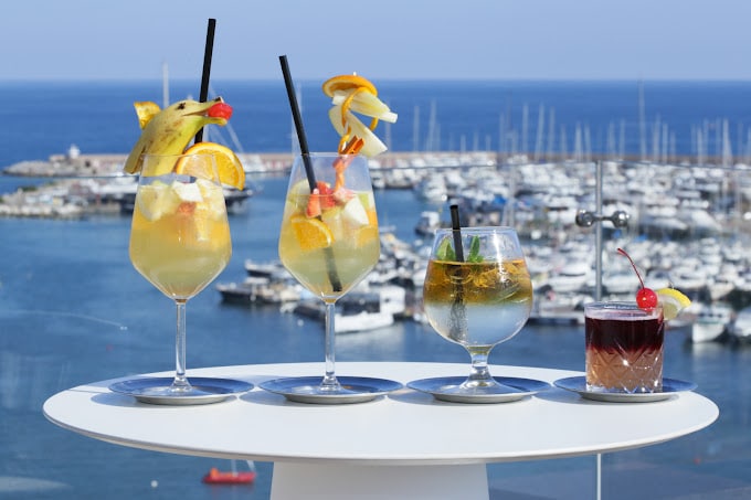 cateva cocktailuri sunt asezate pe o masa de pe terasa din port