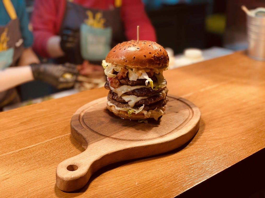 close up cu un burger mare asezat pe un tocator de lemn