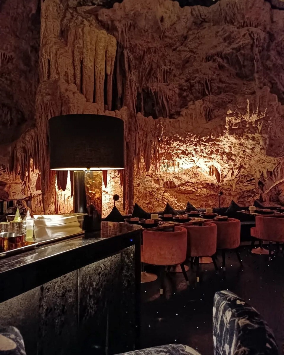 mese de restaurant amenajay intr-o pestra, cu lumina difuza, la The Cave, Bali. Cină extravagantă