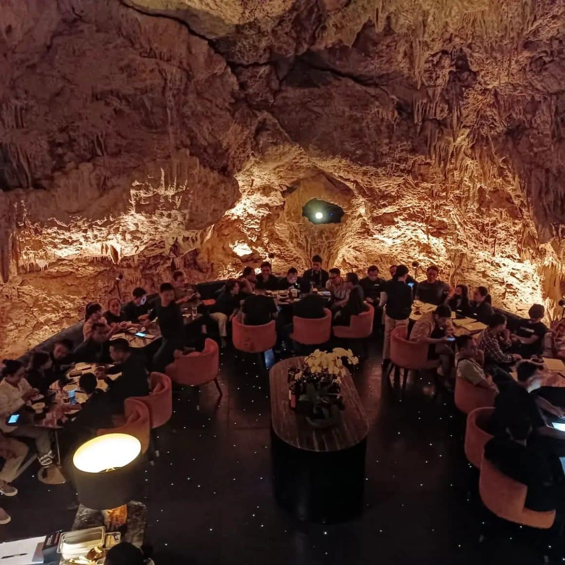 mai multe mese sunt ocupate intr-un restaurant amenajat in interiorul unei pesteri din Bali