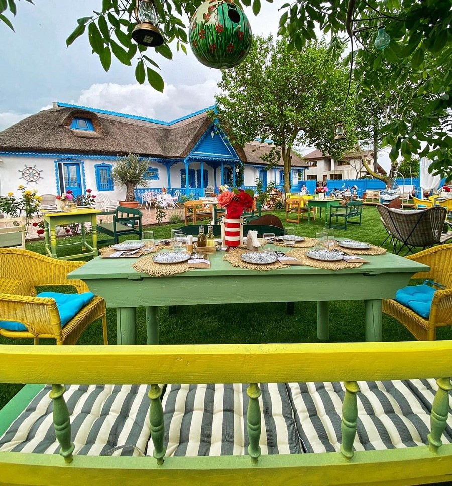 masa si bancuta de lemn, iar in fundal casa traditiola lipoveneasca la Casa Ilinca. Restaurante de la sate, România culinară tradițională