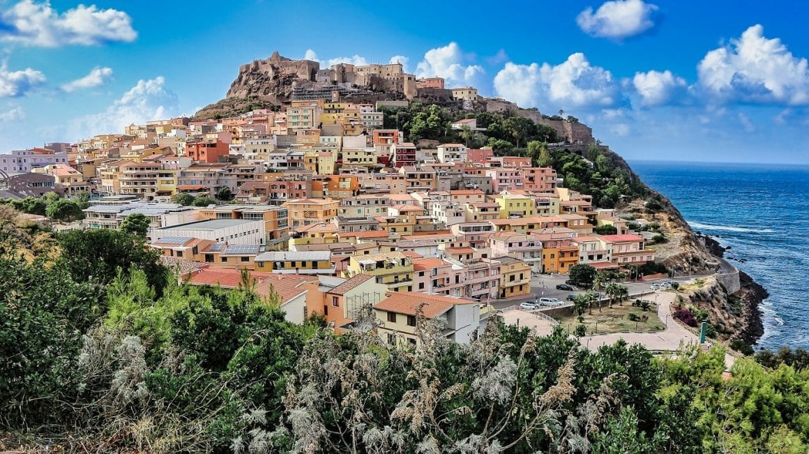Oras;elul Castelardo din Sardinia, cu case asezate pe o colina langa mare