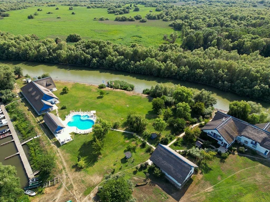 Ansamblul Cherhana Resort fotografiat de sus, cu piscina, si un brat al Dunării acre trece în apropiere